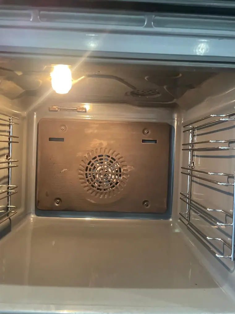 The same oven interior after cleaning and a new element, clean and lit