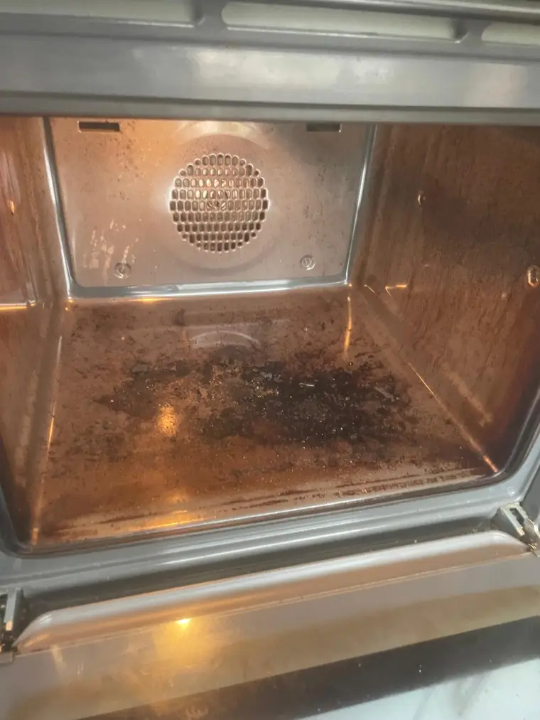 The inside of an oven before work, with heavy baked-on grease across the base and back